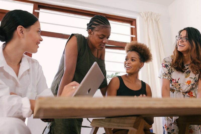 A group of women converse around a table