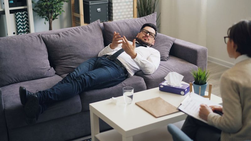 A man lies on a couch and talks to a mental health professional
